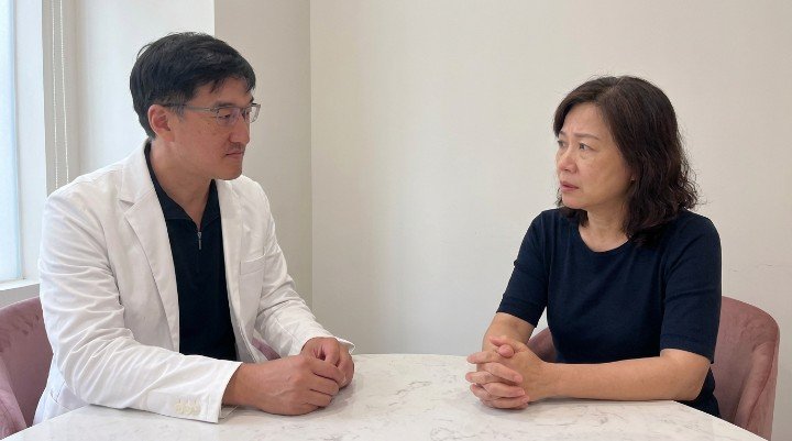 醫師穿著白袍，表情專業，正在向患者講解甲狀腺亢進的副作用與應對方法。 患者在門診中，對著醫師提出關於甲亢副作用導致體重增加的疑問，神情略帶憂慮。 專業的醫學圖表，清楚標示出甲狀腺亢進常見的副作用及其可能影響。 一個擺盤精緻的健康餐盤，展示了適合甲亢副作用患者的低碘飲食建議。